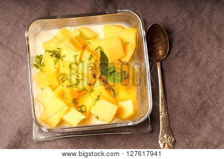 dessert pudding served with mango and chopped mint leaves