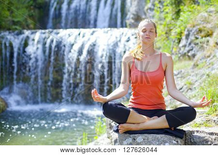 Young women practise yoga by day in nature