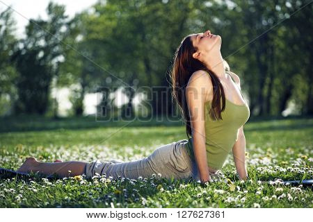 Young women practise yoga by day in nature
