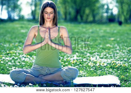 Young women practise yoga by day in nature