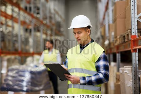 wholesale, logistic, people and export concept - man with clipboard in reflective safety vest at warehouse