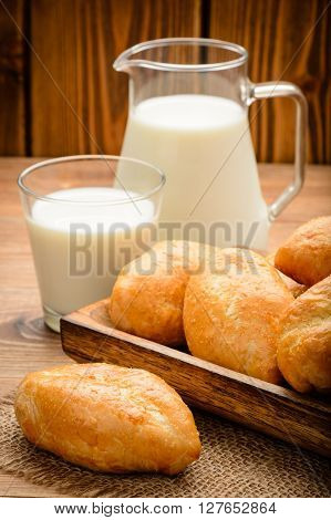 Traditional  russian pastry piroshki and milk on wooden table.