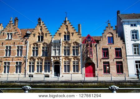 The row of colorful traditional houses in Brugge, Belguim against blue sky
