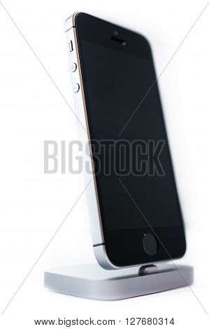 PARIS FRANCE - APR 21 2016: Front view of the new Apple iPhone SE in docking station combining the updated processor 4K rear camera touch id retina display