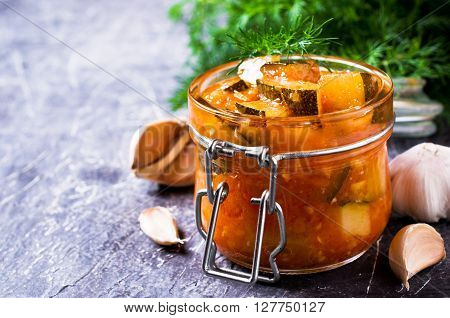 Homemade canned zucchini with vegetables in red sauce. Selective focus.