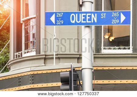 Street sign of Queen Street in Auckland - Urban concept and road direction in the biggest city of New Zealand - Australasian world famous destination with warm filter and enhanced sunshine halo