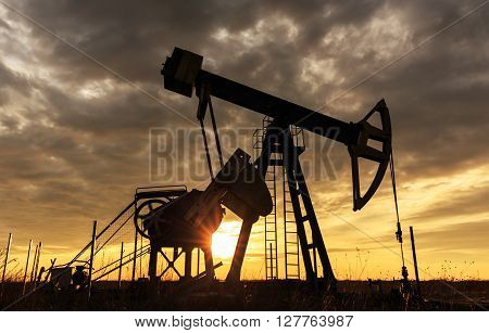 Sunset sky with profiled oil and gas well pump