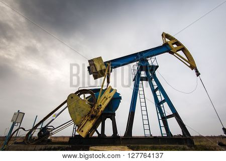 Sunset sky with profiled oil and gas well pump