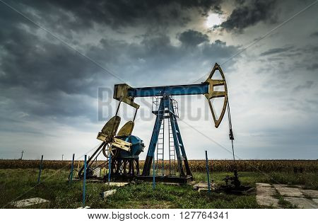 Sunset sky with profiled oil and gas well pump