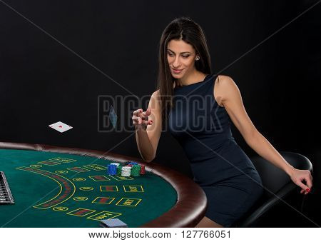 sexy woman with poker cards and chips. Female player in a beautiful black dress, throws a card. Two aces