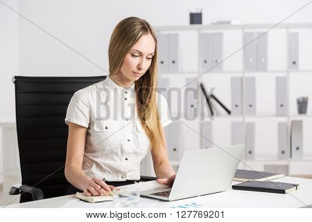 Businesswoman using laptop at office desk, close up