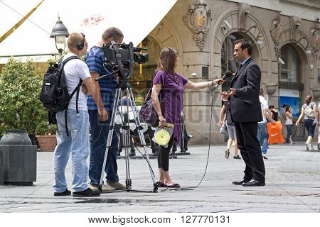 BELGRADE, SERBIA - JUN 9, 2011: RTS cameraman, sound recordist and TV reporter on the street holding an interview with a man in a suit