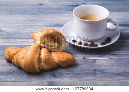 Coffee with freshly baked croissants on the wood background