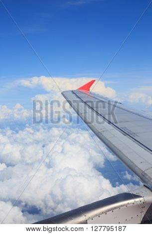 view from aircraft window to see airplane wing and white clouds