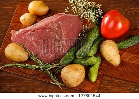 Raw meat with vegetables on a wooden table for a delicious dinner
