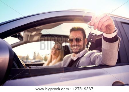Man and woman bying a car.Men sitting in a car and showing car key. Focus on key.