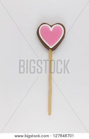 cookies in the shape of pink heart on a wooden stick .