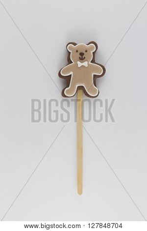 Cookies in the form of a brown bear on wooden sticks . brown teddy bear with a white butterfly .