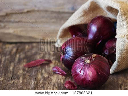 Red onion in a bag on a vintage wooden background. Close-up. Bio healthy vegetables. Copy space background . Selective focus