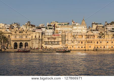UDAIPUR INDIA - 20TH MARCH 2016: A view of part of the City of Udaipur at the lake waterfront during the day close to sunset. People and boats can be seen.