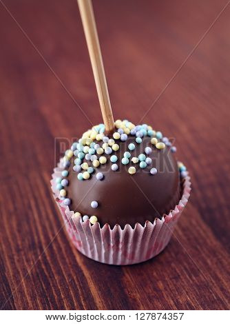 Mini cake on a stick. Chocolate POP CAKE at wrapper on wooden background