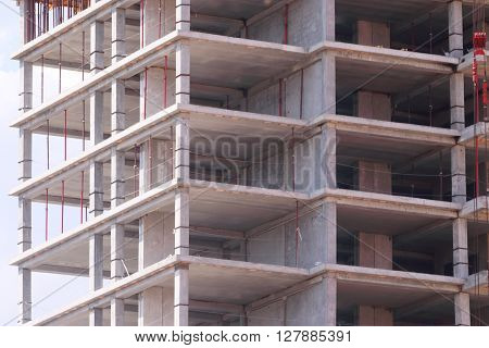 High concrete residential building with skeleton of floors on construction site