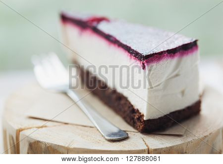 Slice of delicious cheesecake with raspberry on a wooden plate in cafe. Great piece of sweet dessert true delicacy. Close up macro photo