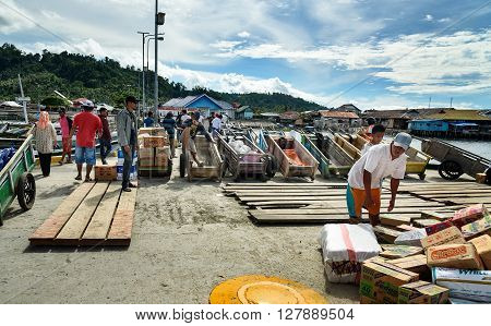 Wakai Indonesia - Dec 16 2015: Wooden carts on the pier. Indonesian men carry goods of the ship from the Ampana. Togean Islands or Togian Islands in the Gulf of Tomini. Central Sulawesi.