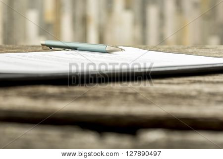 Low angle view of a pen lying on a contract legal paper or document.