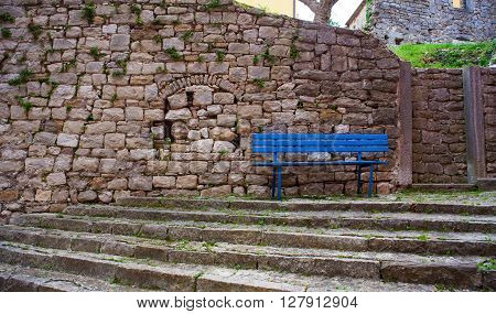 Blue bench next to the stones wall in labin