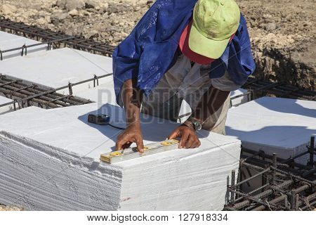 Worker levelling an Iron framework and polyurethane  to build a foundation for a building