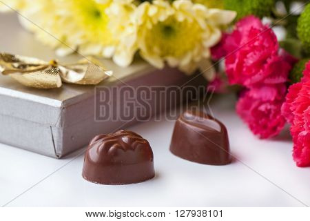 Chocolate Candy And Flowers Over White
