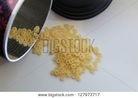 Small dry pasta noodles in tin on background