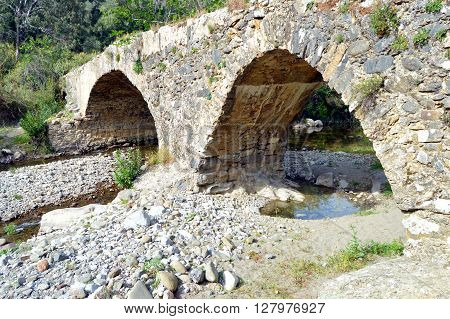 Very former bridge in stones with two arches.