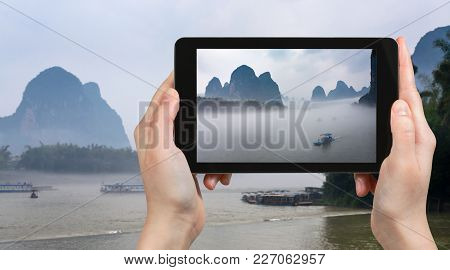 Travel Concept - Tourist Photographs Boats In Mist On River Near Xingping Town In Yangshuo County In