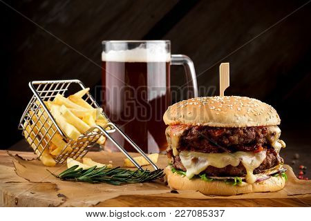 American Burger With Fries On Wooden Board With A Glass Of Beer.