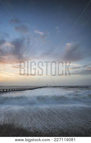 Beautiful Dramatic Stormy Landscape Image Of Waves Crashing Onto Beach At Sunrise