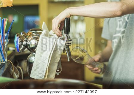 Pouring Fresh Beer. Close-up Of Young Bartender Pouring Beer While Standing At The Bar Counter