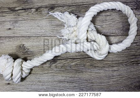 Old Knoted Rope Lays On Wooden Background