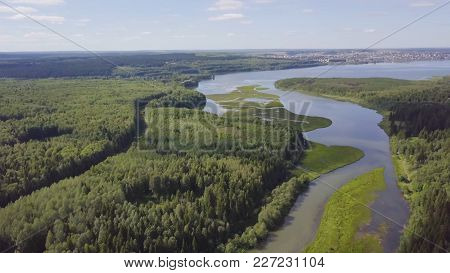 Aerial View Over Sunny Lake Surrounded By Pine Tree Forest Near Town. Clip. During Sunny Summer Day.