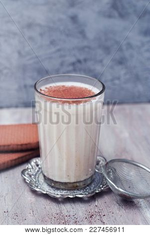 A Glass Of Milk With Cinnamon Or Cocoa Powder With Biscuits On Rustic Background.