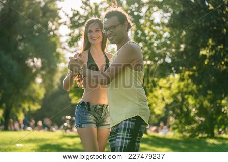 Mann turning woman while dancing Bachata in the sun in park