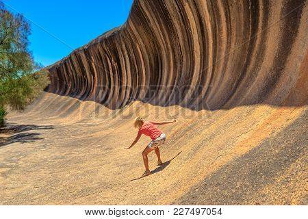 Young Woman Enjoying Surfing On The Wave Rock, A Natural Rock Formation That Is Shaped Like A Tall B