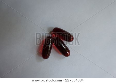 Top View Of Three Red Softgel Capsules Of Krill Oil