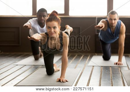 Group Of Sporty Young Afro American And Caucasian People Practicing Yoga Lesson With Smiling Instruc