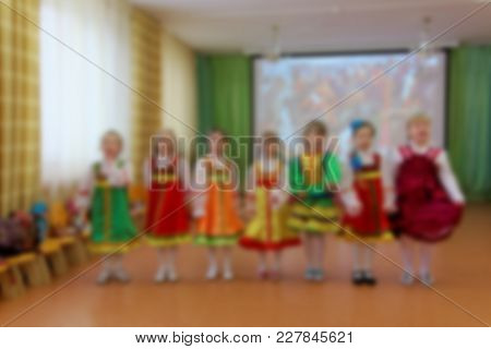 Folk Dances Of Children Theme Abstract Blur Background With Bokeh Effect. Children In Bright Folk Co