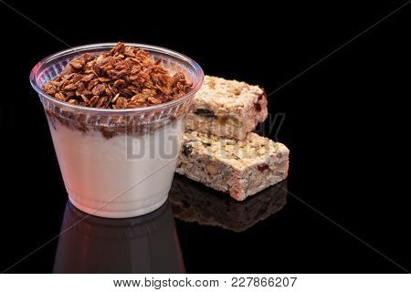 Yogurt With Chocolade Granola And Granola Bar With Fruits And Nuts On Black Background With Copyspac