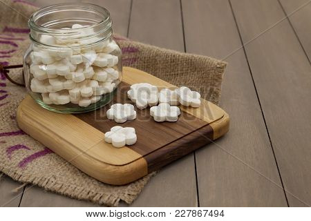 White Coconut Tapioca Cookies Spread On A Wooden Block And In A Glass Jar With A Burlap Cloth.