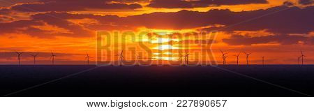 Panorama Sunset Sun At Windmills Offshore Clean Wind Power Farm. Many Energy Stations On Sea Water, 