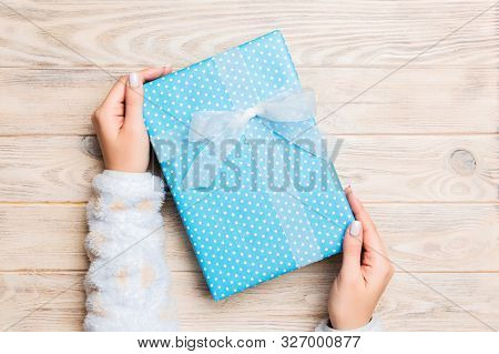 Top View Woman Hands Holding Present Box With Colored Bow On Yellow Rustic Wooden Background With Co